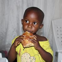Ein kleines Mädchen isst eine Sambusa.