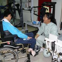 Eine Physiotherapeutin unterhält sich mit einem taiwanischen Kind im Rollstuhl.