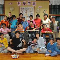 Eine großes Gruppe taiwanischer Menschen mit Behinderungen steht mit Instrumenten zusammen.
